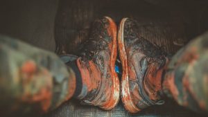 Close-up of muddy boots inside a vehicle, capturing the essence of adventure and rugged outdoor lifestyle.