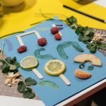 Colorful food art on paper featuring lemons, raspberries, and fresh herbs for a creative craft project.