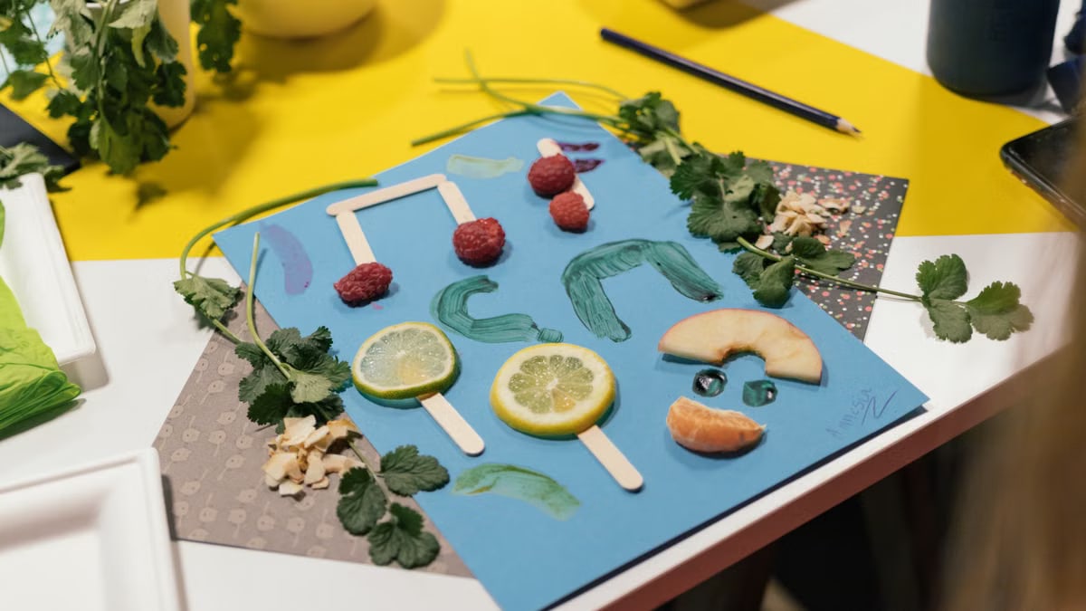 Colorful food art on paper featuring lemons, raspberries, and fresh herbs for a creative craft project.